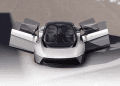 Chrysler Halcyon Concept car parked in desert landscape, sleek design, expansive glass canopy reflecting sunset.