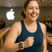 Smiling woman jogging through Apple Store wearing Apple Watch with fitness rings, cheered on by staff