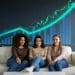 Three women crypto investors sitting together with rising investment chart, focusing on long-term wealth strategies.