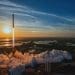SpaceX Falcon 9 rocket launching Crew-10 mission at sunset with smoke and flames