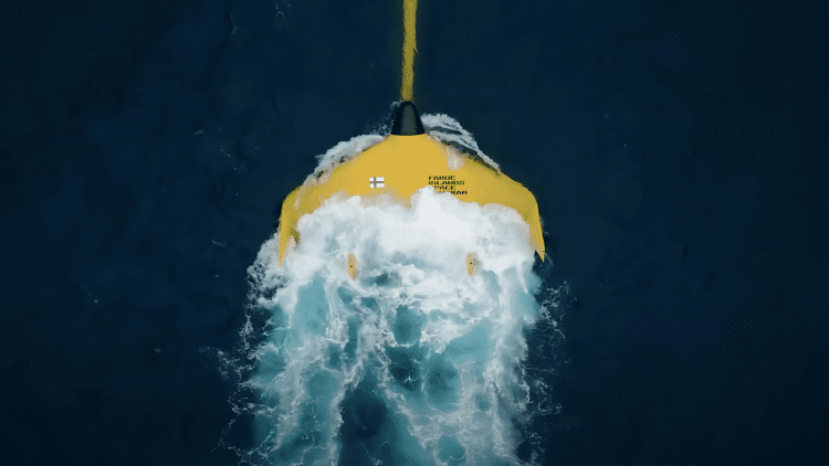 Top-down view of a bright yellow tidal kite from the Faroe Islands Space Program gliding through ocean currents, showcasing lunar-powered energy generation.