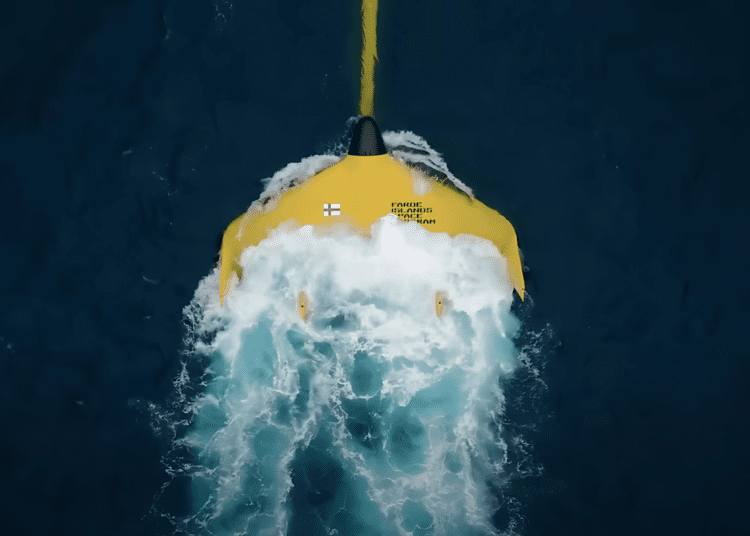 Top-down view of a bright yellow tidal kite from the Faroe Islands Space Program gliding through ocean currents, showcasing lunar-powered energy generation.