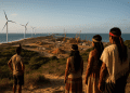 AI-generated photo-realistic image depicting the Pecém port area in Ceará, Brazil, with Indigenous people observing coastal construction and wind turbines, representing the TikTok data center land dispute.