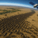 A 3D realistic view of a satellite tracking wildebeest herds across the Serengeti-Mara plains using AI technology, blending innovation with nature.