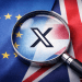 Magnifying glass highlighting the X social media platform logo against the European Union and United Kingdom flags, symbolising regulatory scrutiny over Grok AI deepfake content.