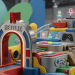 A minimalist editorial photo of a conceptual Netflix Playground gaming hub for kids, featuring sleek colorful structures, gaming controls, and the Netflix logo.