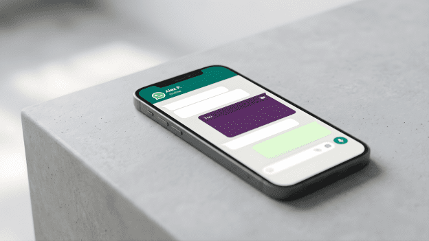 A smartphone on a minimalist grey surface displaying a WhatsApp chat interface with a single vibrant purple message bubble among standard white bubbles.