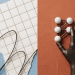 A minimalist 3D photographic editorial illustration representing Claude Opus 4.8 dynamic workflows, featuring a metallic hand interacting with white network nodes on a terracotta background.