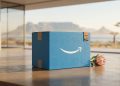 A minimalistic 3D editorial photograph of a blue Amazon Prime delivery box with embossed South African cultural symbols, featuring Table Mountain and a King Protea flower in the background.