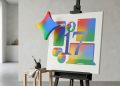 A minimalistic 3D render of the Google Gemini star logo floating next to a white canvas on an easel, featuring silhouettes of a Pixel phone, watch, and Chromebook in Gemini gradient colours alongside the number 17.