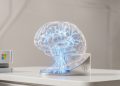 A high-quality 3D render of a glowing glass brain structure on a sleek metallic base, symbolising the Microsoft and Mayo Clinic medical AI partnership.