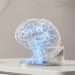A high-quality 3D render of a glowing glass brain structure on a sleek metallic base, symbolising the Microsoft and Mayo Clinic medical AI partnership.
