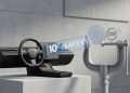 Minimalist 3D studio shot of a Tesla steering wheel console next to a metallic regulatory clamp scrutinising a "10X Safer" glass data block, symbolising EU regulatory scepticism.