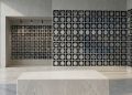 A minimalist editorial display of a grid containing detailed medical brain scans and ultrasound imaging slices, seamlessly integrated onto a concrete gallery wall in a modern, brightly lit architectural space with a marble pedestal in the foreground.