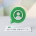 A minimalist 3D editorial graphic of a green chat bubble containing a user icon, hovering over a clean white card with '@USER_IDENTITY' to symbolise WhatsApp rolling out usernames for enhanced user privacy.