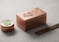 A minimal editorial 3D photograph showing a stack of metallic copper blocks engraved with '45M' alongside a stack of coins featuring the green Cash App logo and a brass ruler engraved with 'STATE PROBE' on a clean concrete background.