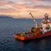 A cable-laying repair ship stationed at sea during sunset, deploying a subsea fibre-optic cable to maintain internet connectivity across Africa.